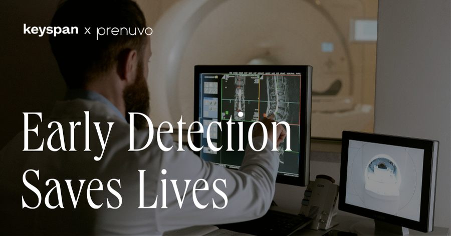 A doctor reviewing a full-body MRI scan on a digital monitor with the text "Early Detection Saves Lives" and the Keyspan x Prenuvo logo.
